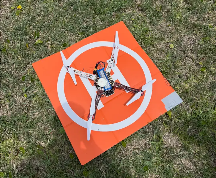 Quadcopter drone on an orange landing pad in the grass