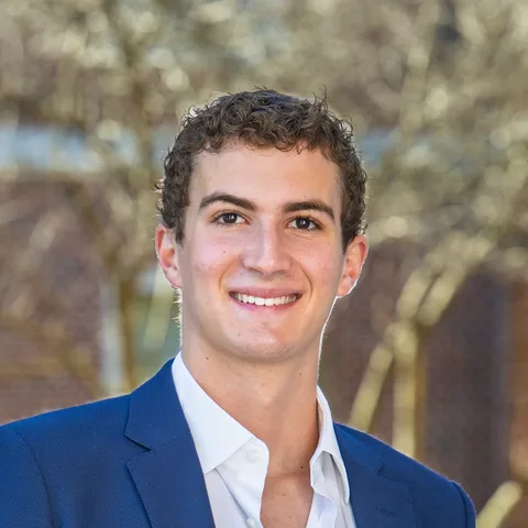 Eli Paresky, smiling, in a blue blazer and white shirt