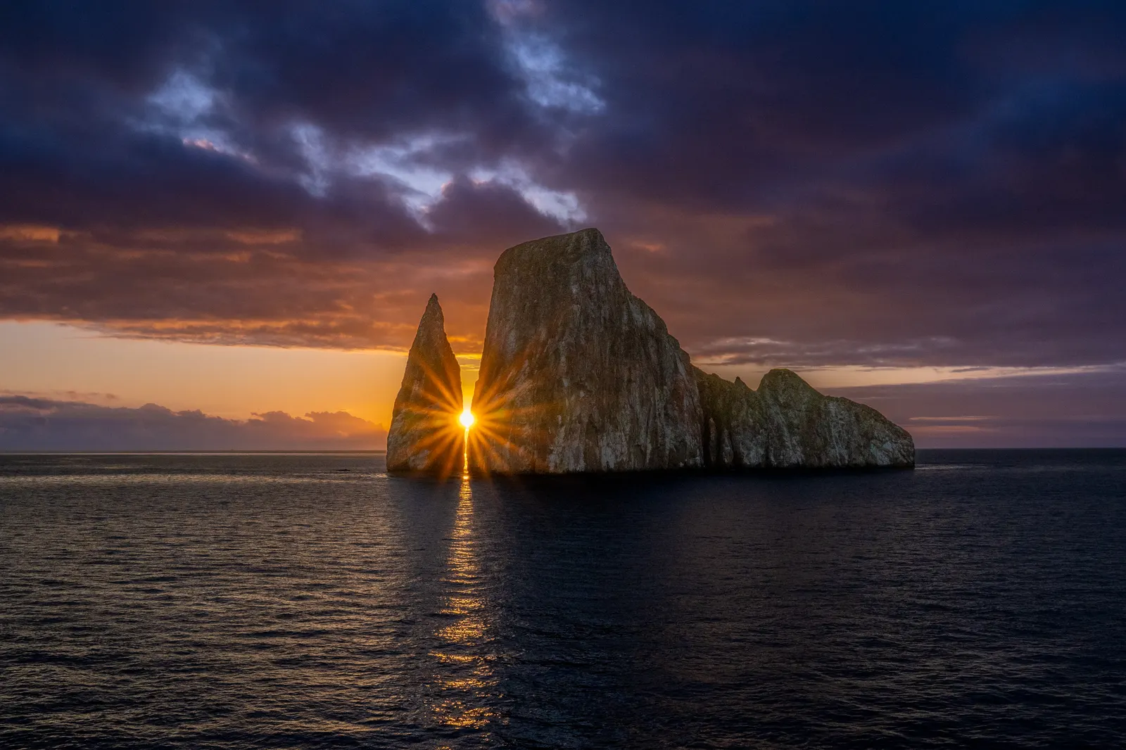 Kicker Rock at sunset, the sun shining through a gap in the rock