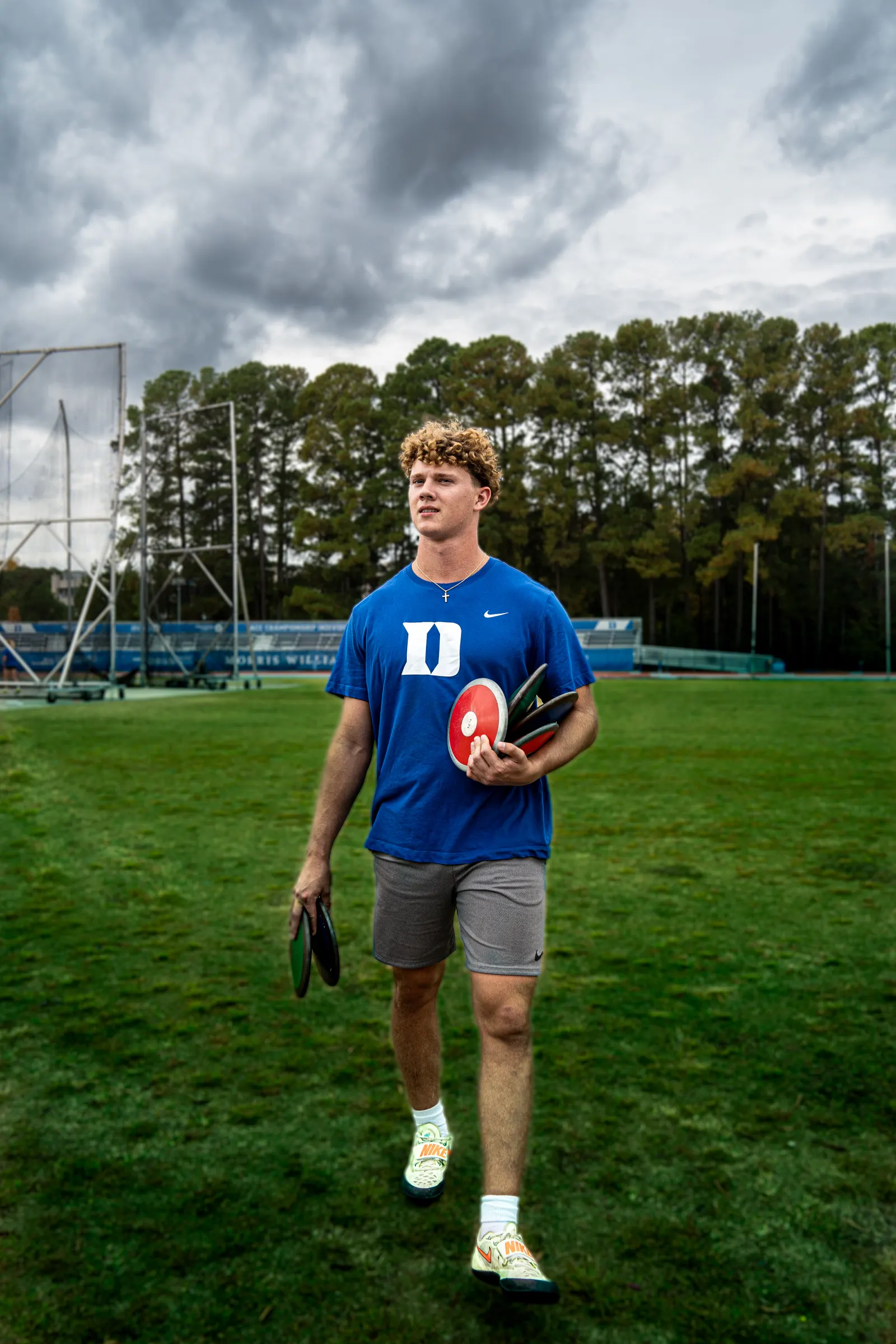 Thrower in a Duke shirt walking across the field holding a discus