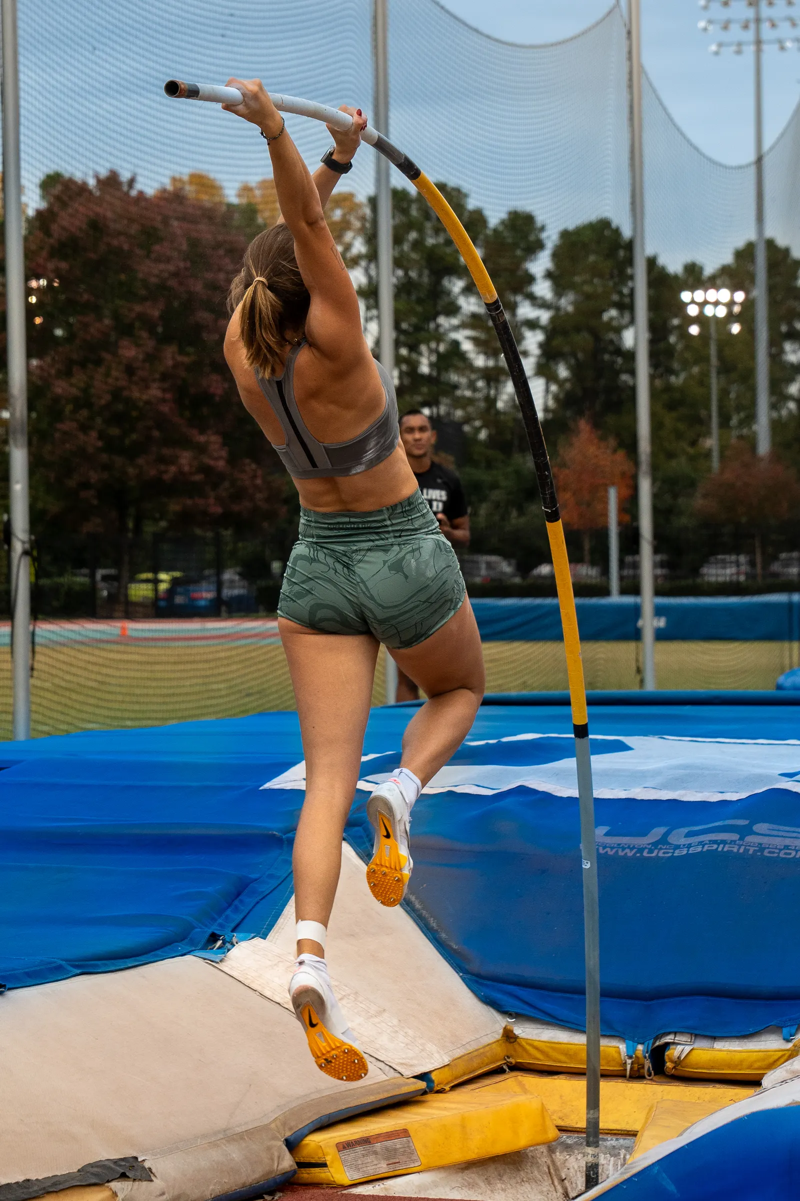 Pole vaulter rising off the runway, seen from behind
