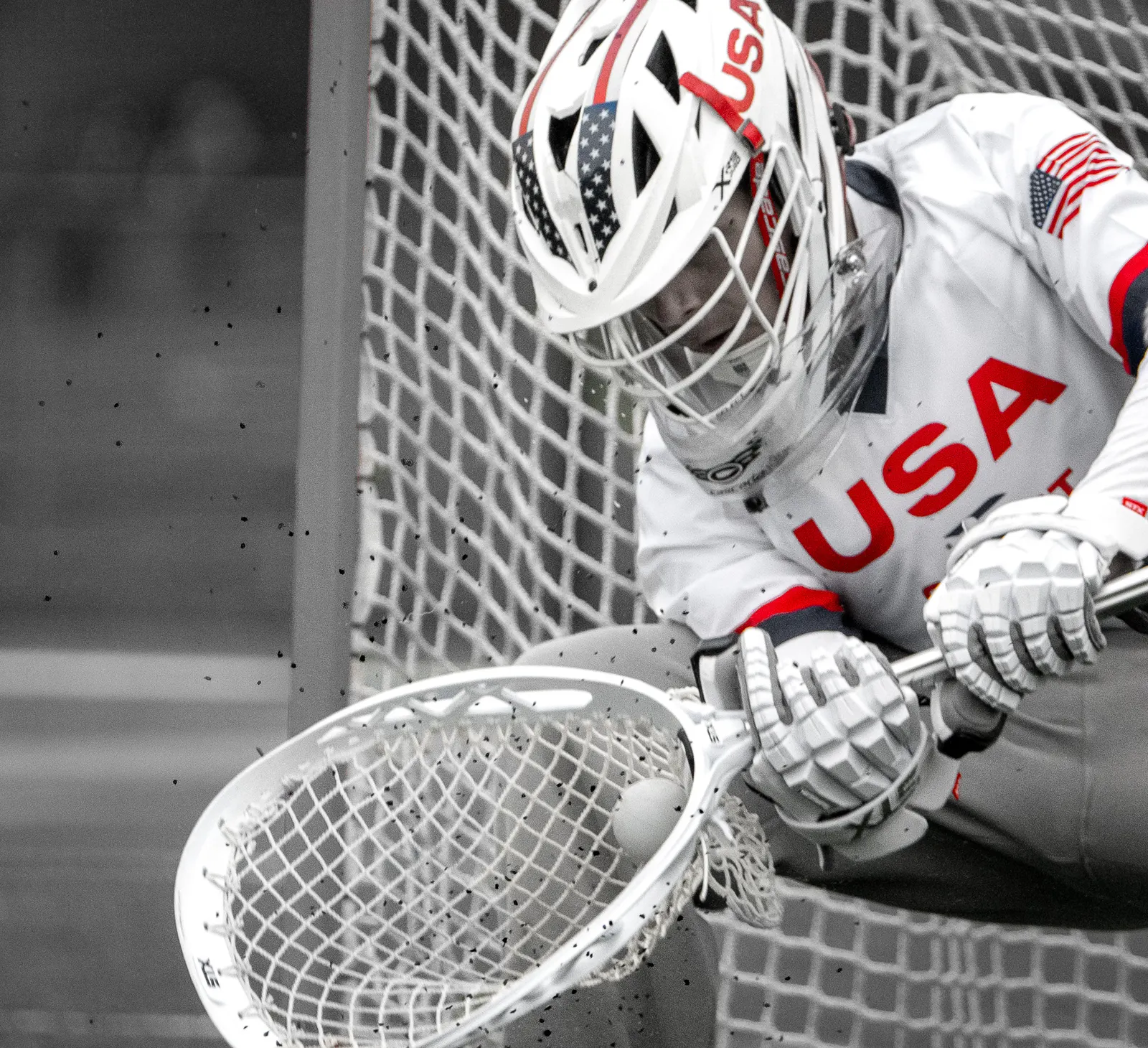 USA lacrosse goalie crouched in goal, black and white with the jersey in color