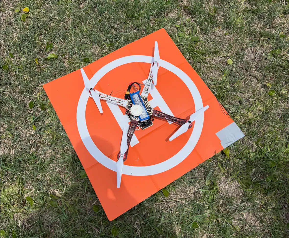 Quadcopter drone on an orange landing pad in the grass